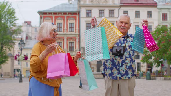 Senior Couple Grandmother Grandfather Tourists with Bags After Shopping in Mall During Black Friday alt