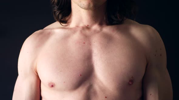 A strong shirtless white man flexing his upper body chest muscles in the gym after a tough fitness t alt