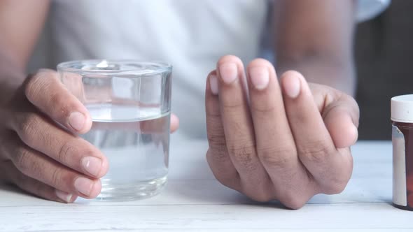 Young Man Holding Pills and Glass of Water with Copy Space alt