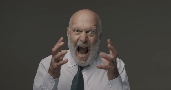 Angry aggressive corporate businessman shouting at camera, he is stressed and frustrated