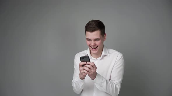 A Young Guy Expresses Joy While Looking at His Smartphone
