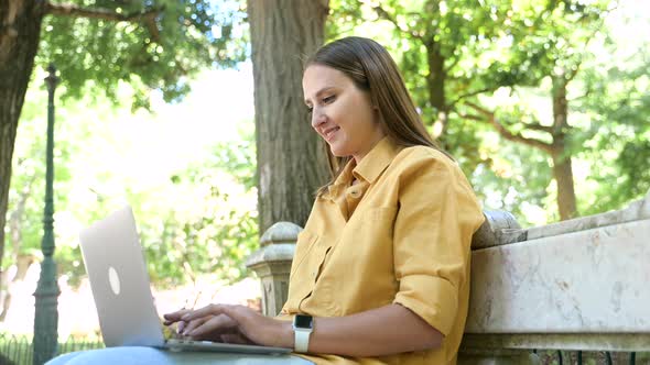 Positive Female Freelancer Enjoying Remote Work Sitting in the Park Smiling Woman Using Laptop