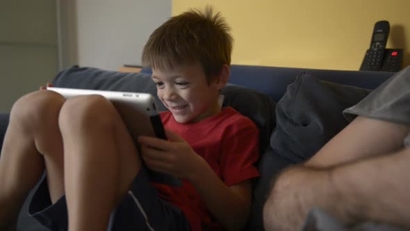 Child Play with Tablet on Sofa at Home with His Dad