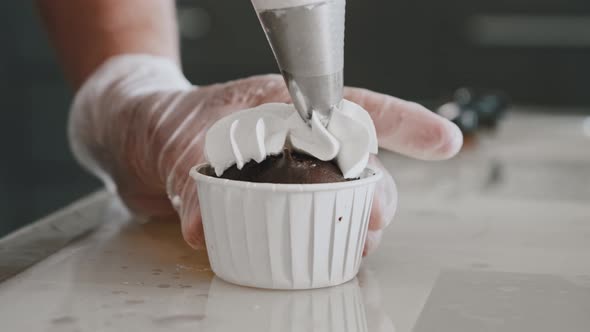 Woman Chef Applying White Cream on the Top of a Cupcake alt