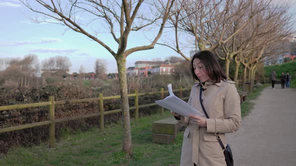 A Girl in the Park Reads the Text on the Sheets alt