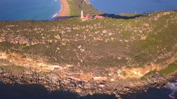Aerial revealing shot of Barrenjoey Head Lighthouse on the top of headland sandstone rock in sunrise alt