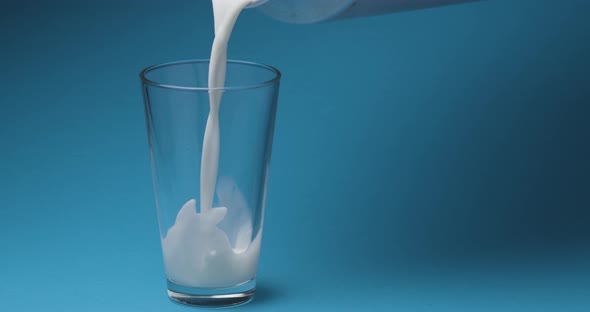 Milk is poured into a milk glass on a blue background alt