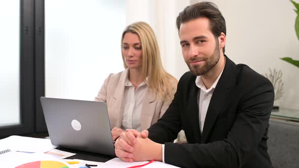 Young Attractive Man and Woman Working with Papers and Laptop in Modern Office