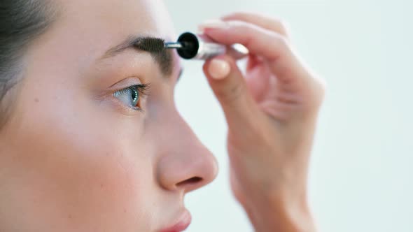 Female Hand Combing Brow Young Beautiful Woman Using Brush or Mascara Closeup alt