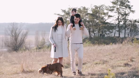 Young Happy Family with Son and Dog Are Walking in the Field alt