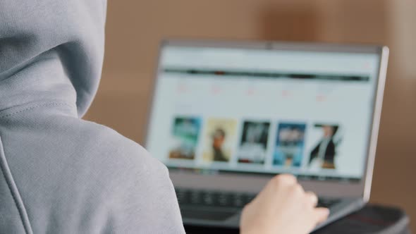 Rear View Unknown Hacker Young Programmer Web Designer in Hood Look at Laptop Display Develop alt