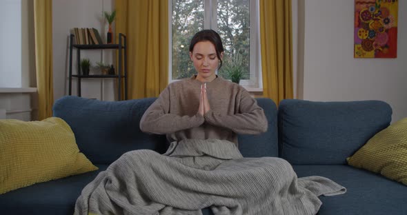 Front View of Calm Lady Meditating at Home with Joined Palms in Namaste Mudra. Elegant Woman Sitting