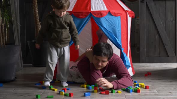Father and son play in blocks and sitting in a small children's house