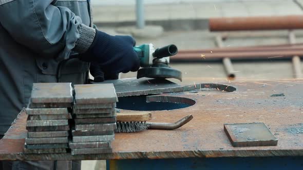 Worker on Workbench Processes Iron Sheets with Grinding Tool and Sparks Fly