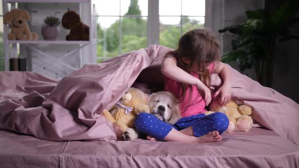 Joyful Child Hiding Under Blanket with Puppy Pet alt