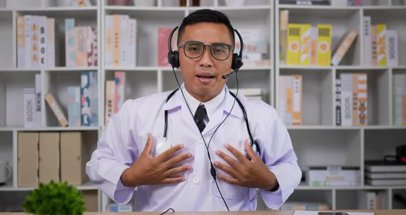 Doctor with headset making conference call and looking at camera alt