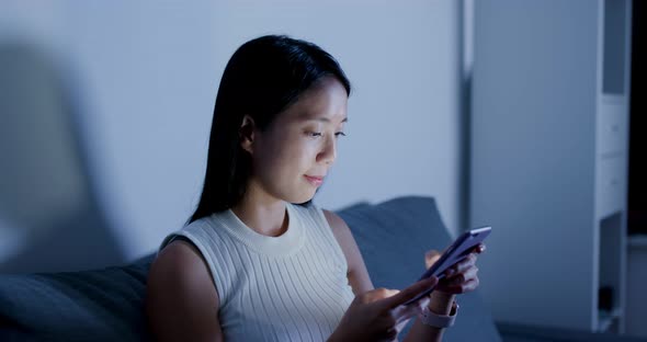 Woman Search on Smart Phone and Sit on Sofa at Home alt