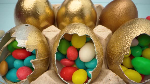 Golden Decorative Easter Eggs Filled with Colorful Candies on Wooden Table Close Up