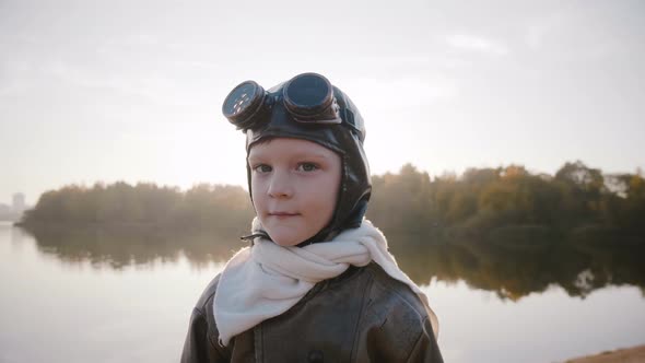 Little Boy in Vintage Pilot Costume with Scarf and Glasses Looking at Camera Smiling alt
