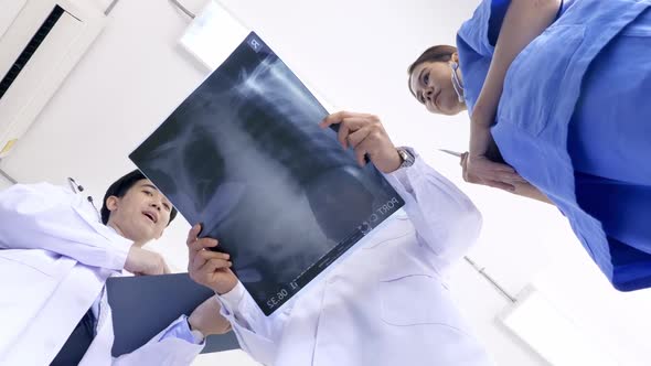 Doctor and medical assistants discussing about diagnosis result on x-ray film. alt