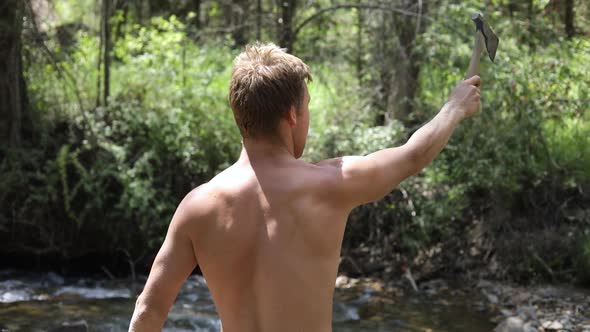 Slow motion shot of a shirtless man practicing his axe throwing skill by trying to throw his hatchet alt