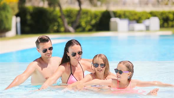 Happy Family of Four in Outdoors Swimming Pool alt