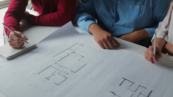 Young People Studying New Blueprints at Office alt