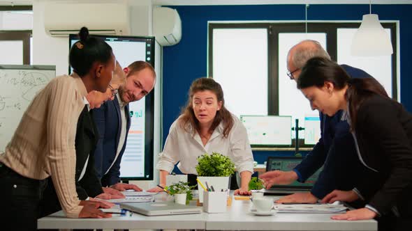Diverse Team of Workers Talking Looking at Documents and Analyzing Graphs alt