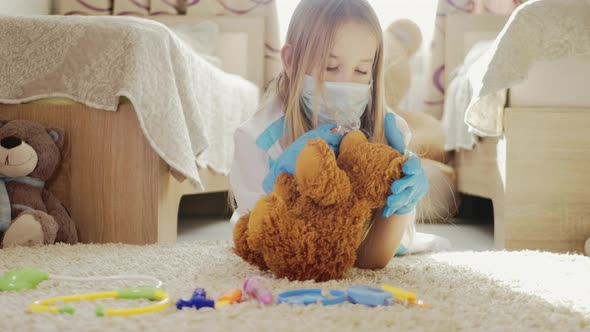 Beautiful Little Girl Playing Doctor with Teddy Bear at Home alt