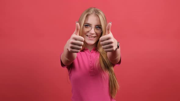 Portrait of Attractive Young Woman Showing a Thumbs Up on Red Background alt