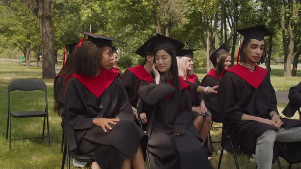 Happy Multiracial Classmates Greeting Each Other at Graduation Ceremony alt