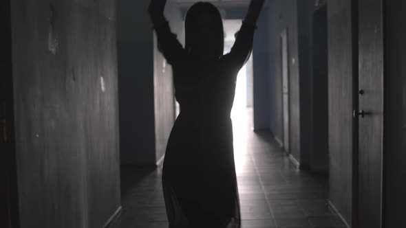 Silhouette of Excited Woman Dancing in Hallway