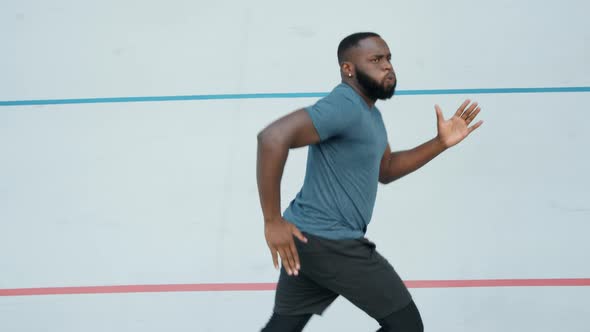 Man Jogging on Running Track. Runner Breathing During Cardio Training Outdoors alt