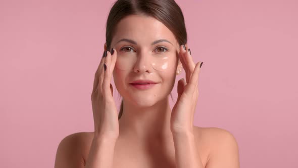 30s Brunette Woman Makes an Under Eye Massage with Gel Eye Patches on