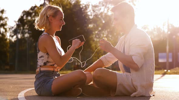 Happy Couple with Smartphone and Earphones in City alt