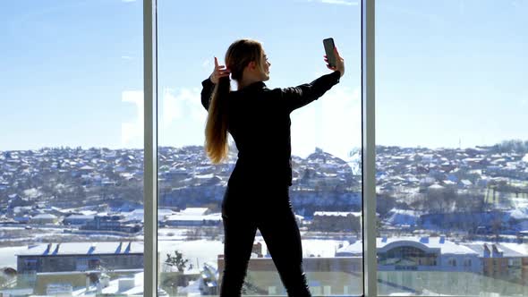 Pretty young businesswoman making selfie at workplace alt