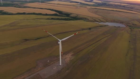 Aerial view of windmill is spinning against the backdrop of a beautiful sunset sky. Renewable energy alt