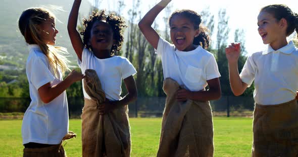 Children playing a sack race in park alt