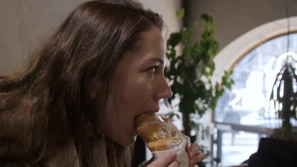 Young Woman Eating Delicious Baked Croissant in Cafe