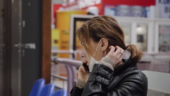 A Business Woman in a Protective Mask Communicates in a Shopping Center