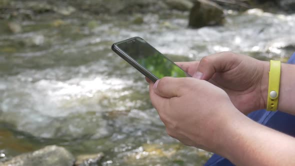 Browse Internet or Type Text Message on Black Smartphone on Mountain Stream Background