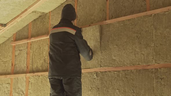Man Laying Insulation in a Wall under Roof