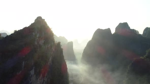 Aerial footage of beautiful sunrise over foggy karst mountain peak landscape alt