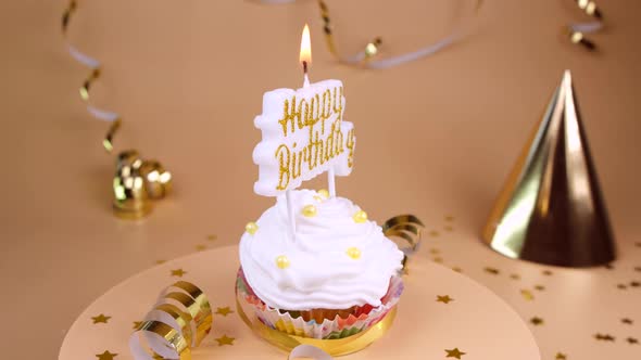 Birthday Cake or Cupcake with Burning Candle with the Inscription Happy Birthday on a Beige