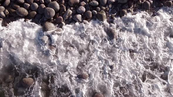 Winter Aerial Flight Top Over Waves Rolling on Artic Ocean Shore with Round Stones Ocean Waves at alt