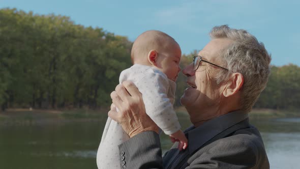 Funny Game and Laugh of Caucasian Old Man and Baby Girl in Domestic Comfort. Wrinkled Skin of alt