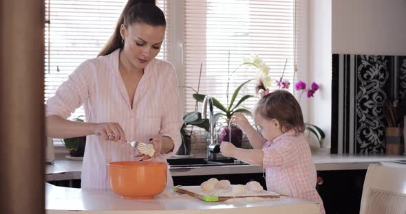 Mother Cooking Together with Little Daughter at Kitchen