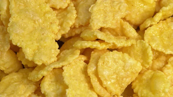Crispy corn flakes rotating in macro, dry healthy breakfast. Honey cornflakes for healthy cereal alt