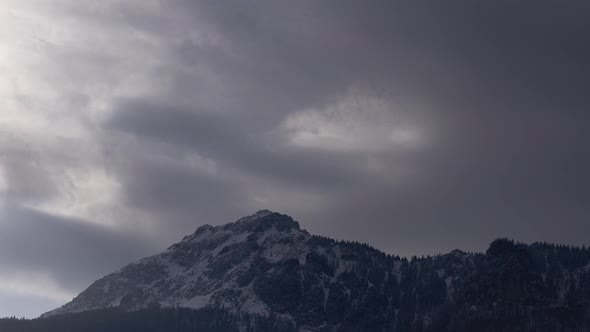 Dense clouds over the rocky peak. Windy winter weather. Clouds and fog alt