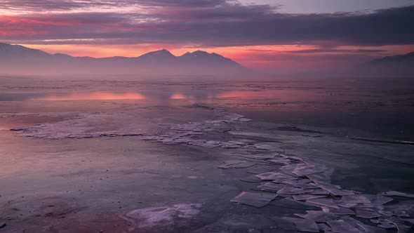 Timelapse over frozen lake during colorful sunrise with cracked ice alt